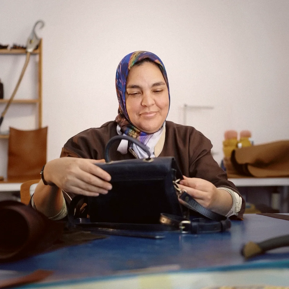 Moroccan leather artisan presenting a finished handbag