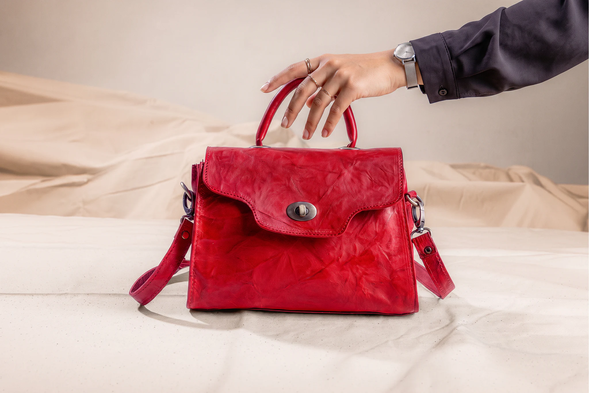 Sac à main marocain en cuir rouge posé sur un tissu neutre